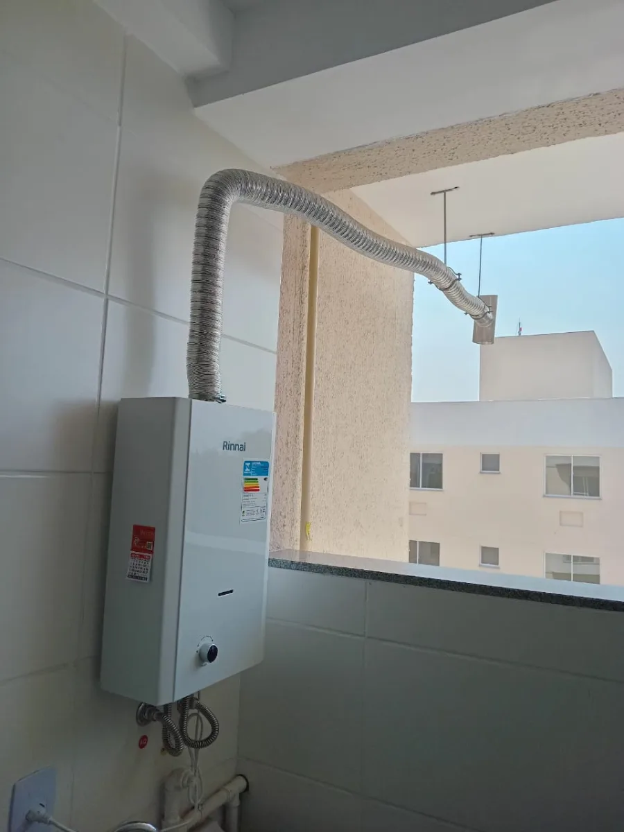 Aquecedor a gás Komeco instalado em área externa, com ligações de água e gás aparentes